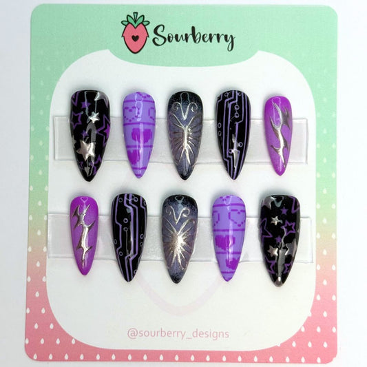 Cyber Butterfly Nails. The thumb nail is black with purple and silver stars on it. The index nail is purple with pixel hearts on it. The middle nail is black with a purple aura and a silver butterfly. The ring nail is also black and it has a circuit board pattern. The pinky nail is purple with a silver cyber sygil on it.
