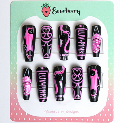 Step on the Gas nail set. The set is black and pink themed. The thumb nail has a racecar, the index nail has a neon design with hearts and starts, the middle nail has a car key and a speedometer, the ring nail has a neon license plate that says luv pink, and the pinky nail has fuzzy dice on them. 